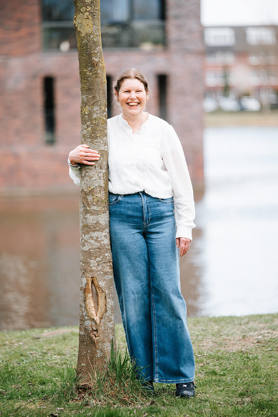 Joline staat tegen een boom bij het water.