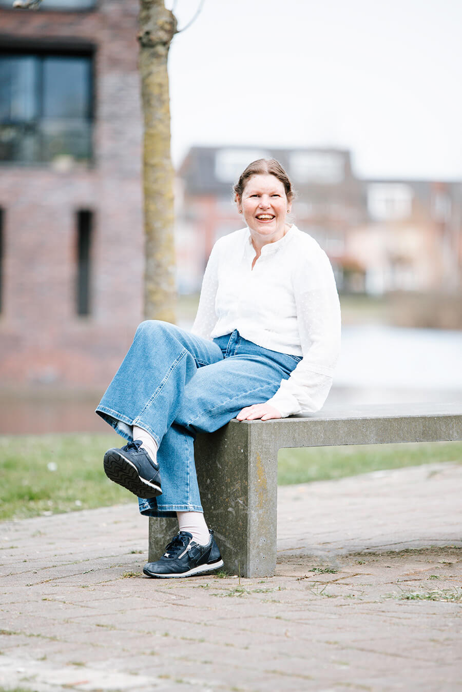 Joline zit op een bankje op straat. Ze lacht.