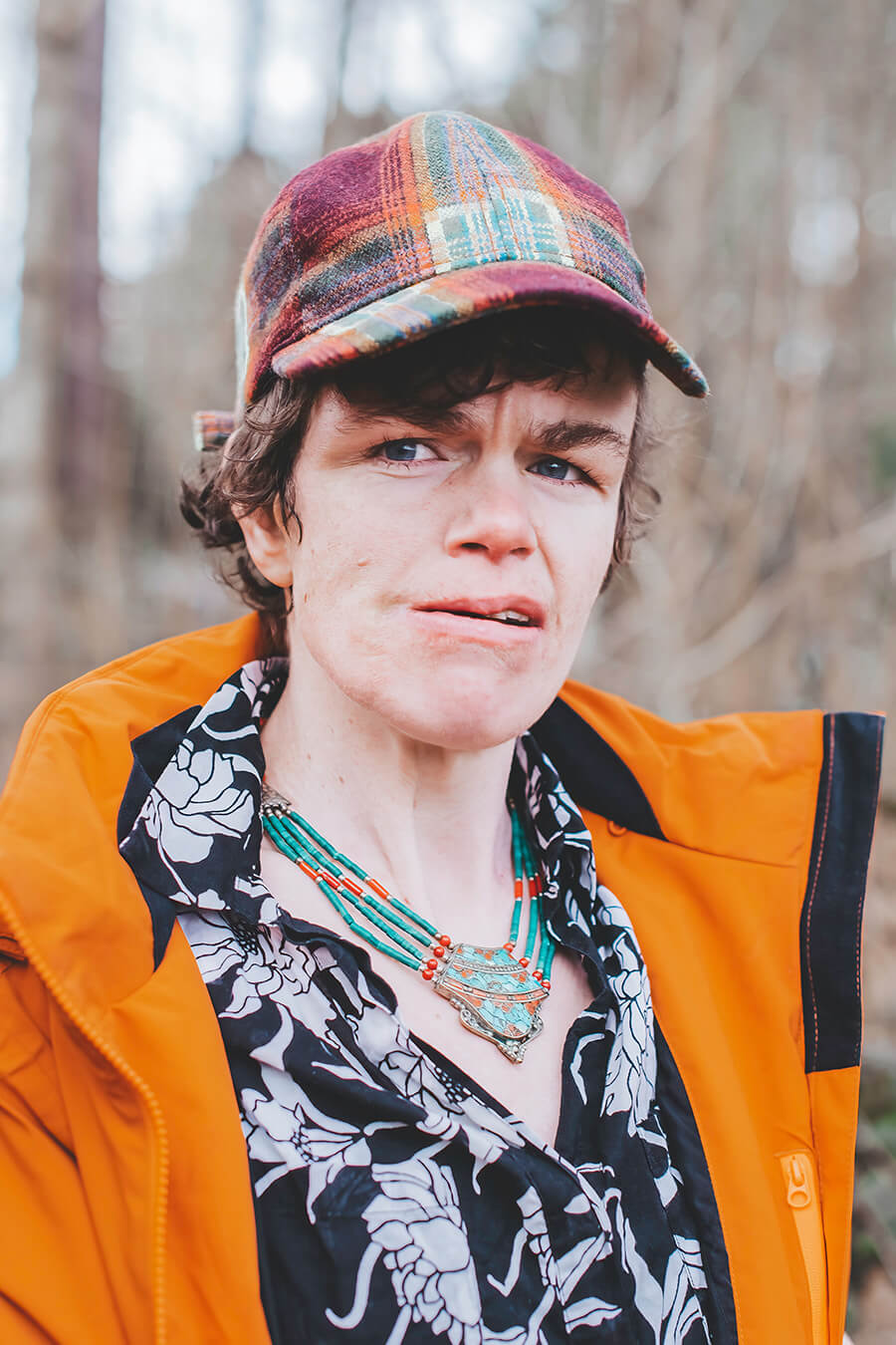 Thiandi, van dichtbij in het bos. Met een feloranje jack en een pet.